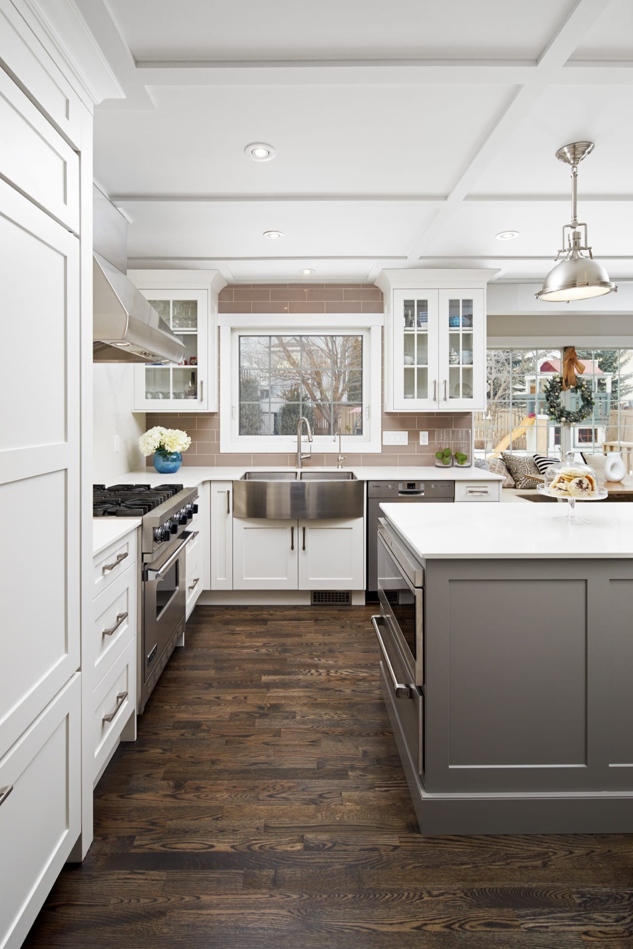 Transitional style kitchen with a perimeter of white shaker cabinetry, a grey island and stainless kitchen accessories.