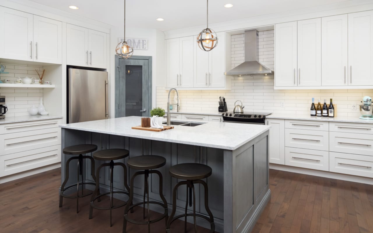 Transitional style kitchen with white shaker cabinets, white subway tile, and a blue-grey island.