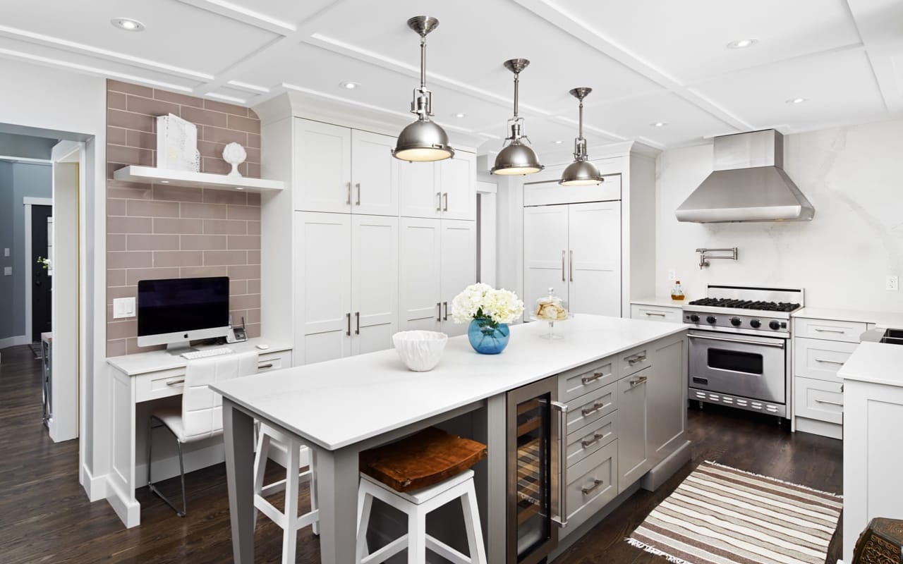 Modern kitchen with black cabinetry, grey countertops, and light wood floors.