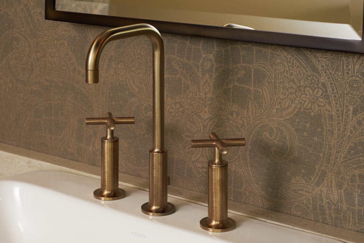 Closeup of a gold bathroom faucet with a white sink.