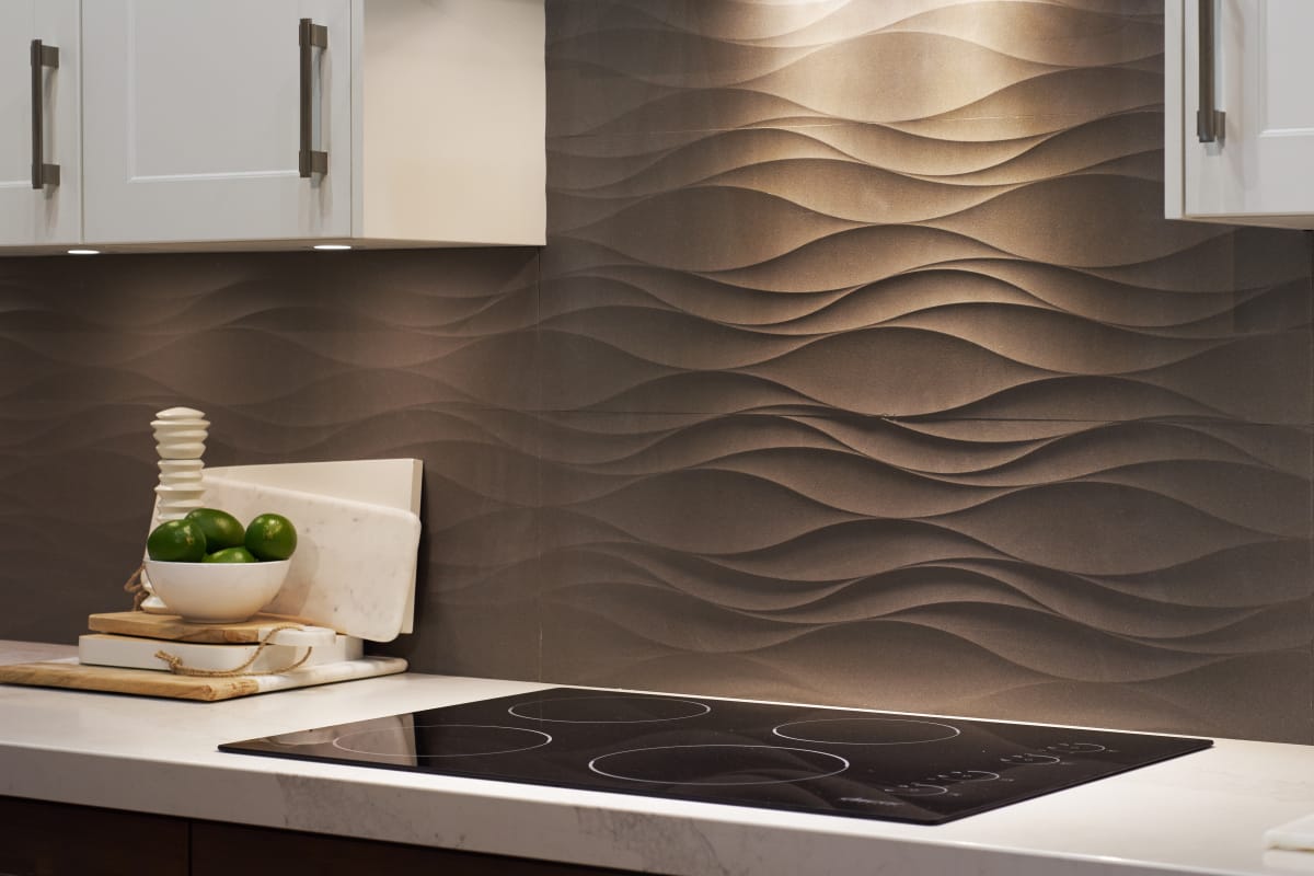 Closeup of a kitchen range with grey wavy backsplash detailing.