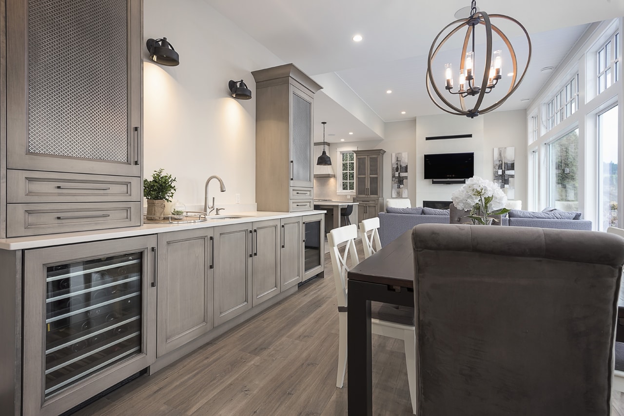 A soft neutral brown hutch located in a dining room. The hutch has tall cabinets, a sink, and a built-in bar fridge.