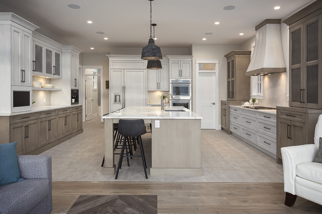 A shot of a kitchen from a dining room. The kitchen is a mixture of soft white and brown cabinets with traditional stylings.