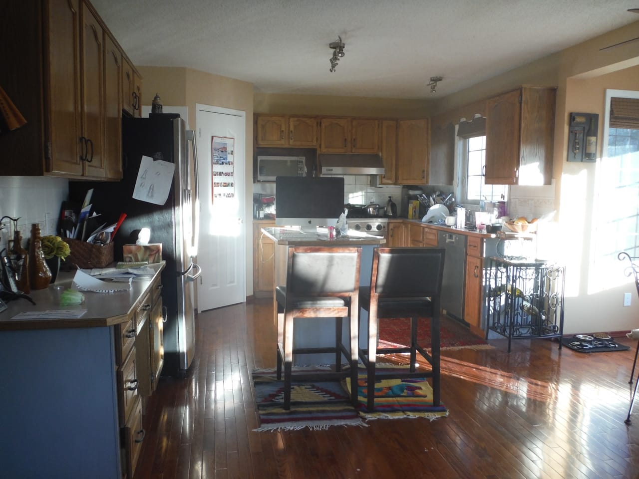 Dark and cluttered kitchen with a small kitchen island with a computer.