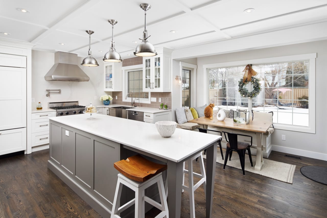 Stainless lighting, appliances, and sink complement the combination of white and grey kitchen cabinetry.