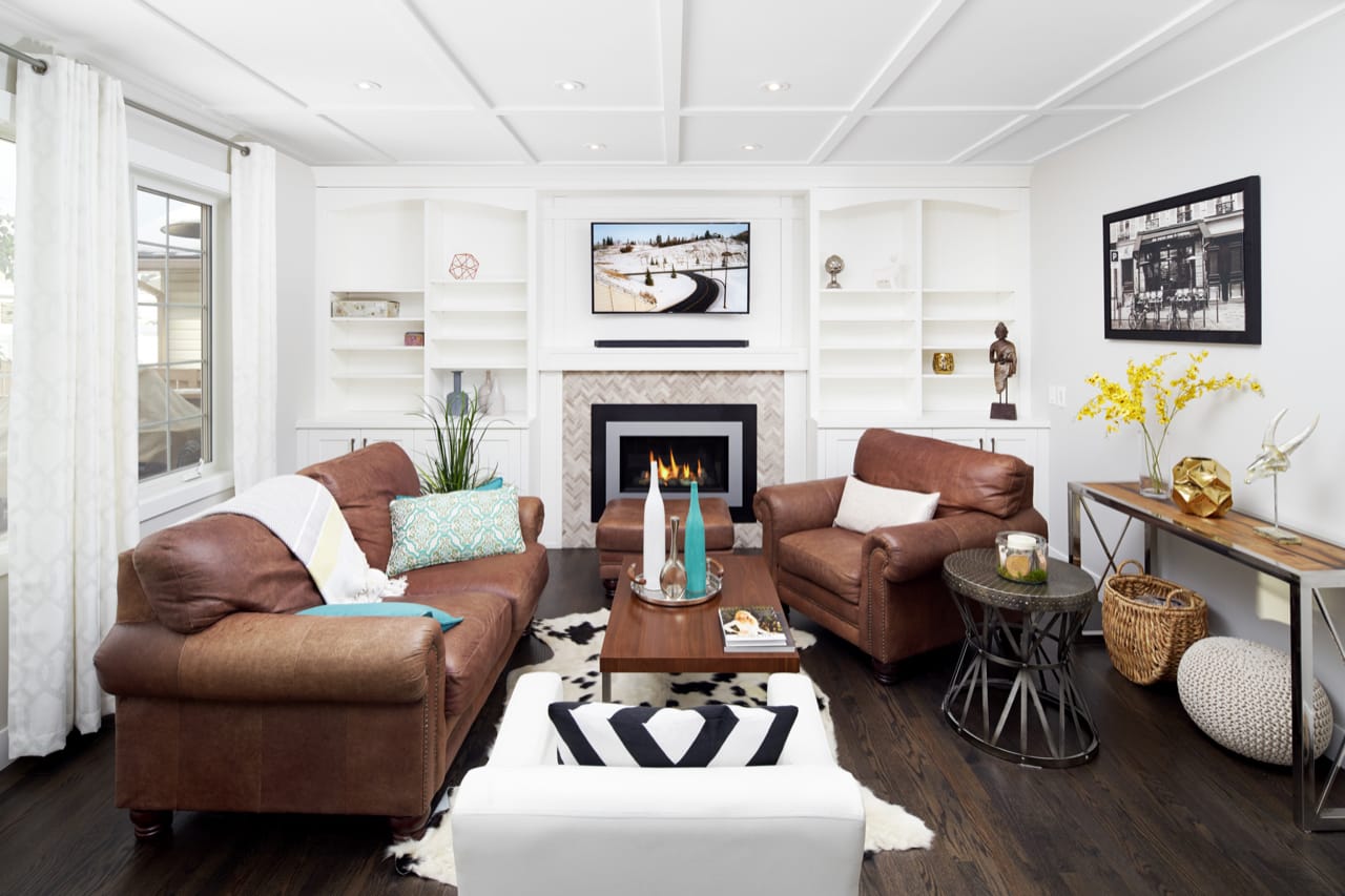 A transitional style family room with white cabinetry and bookshelves. The family room has warm accessories to make the space feel cozy.