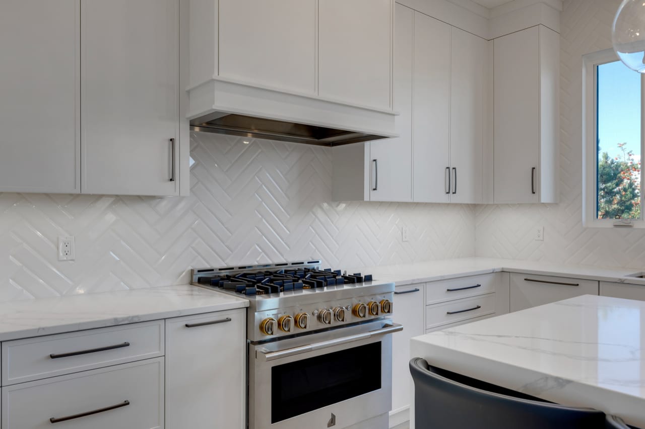A white hoodfan matches the perimeter cabinetry in the kitchen.