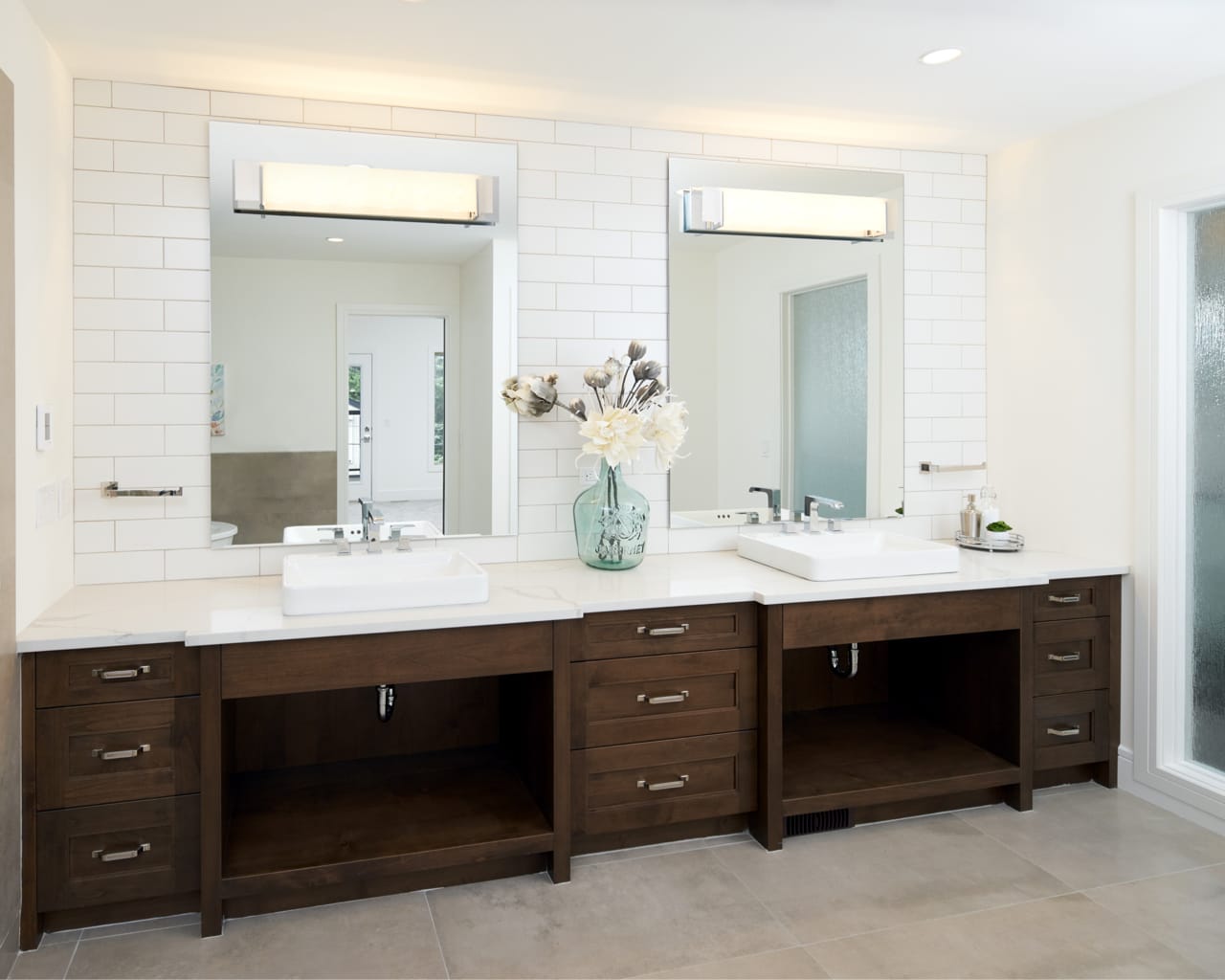 A transitional style bathroom with a large double bathroom vanity with walnut shaker-style cabinets.