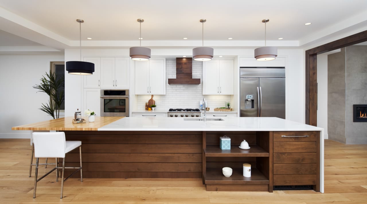 Transistional style kitchen with modern design touches including an island and hoodfan with shiplap detailing and a subway tile backsplash.